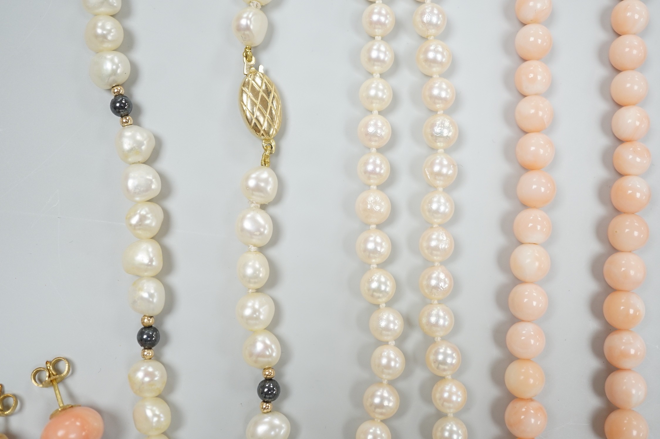 Two modern single strand cultured pearl necklaces, both with 375 clasp, one with hematite beads, longest 42cm, together with two modern coral bead necklaces, one with pair of matching drop earrings.